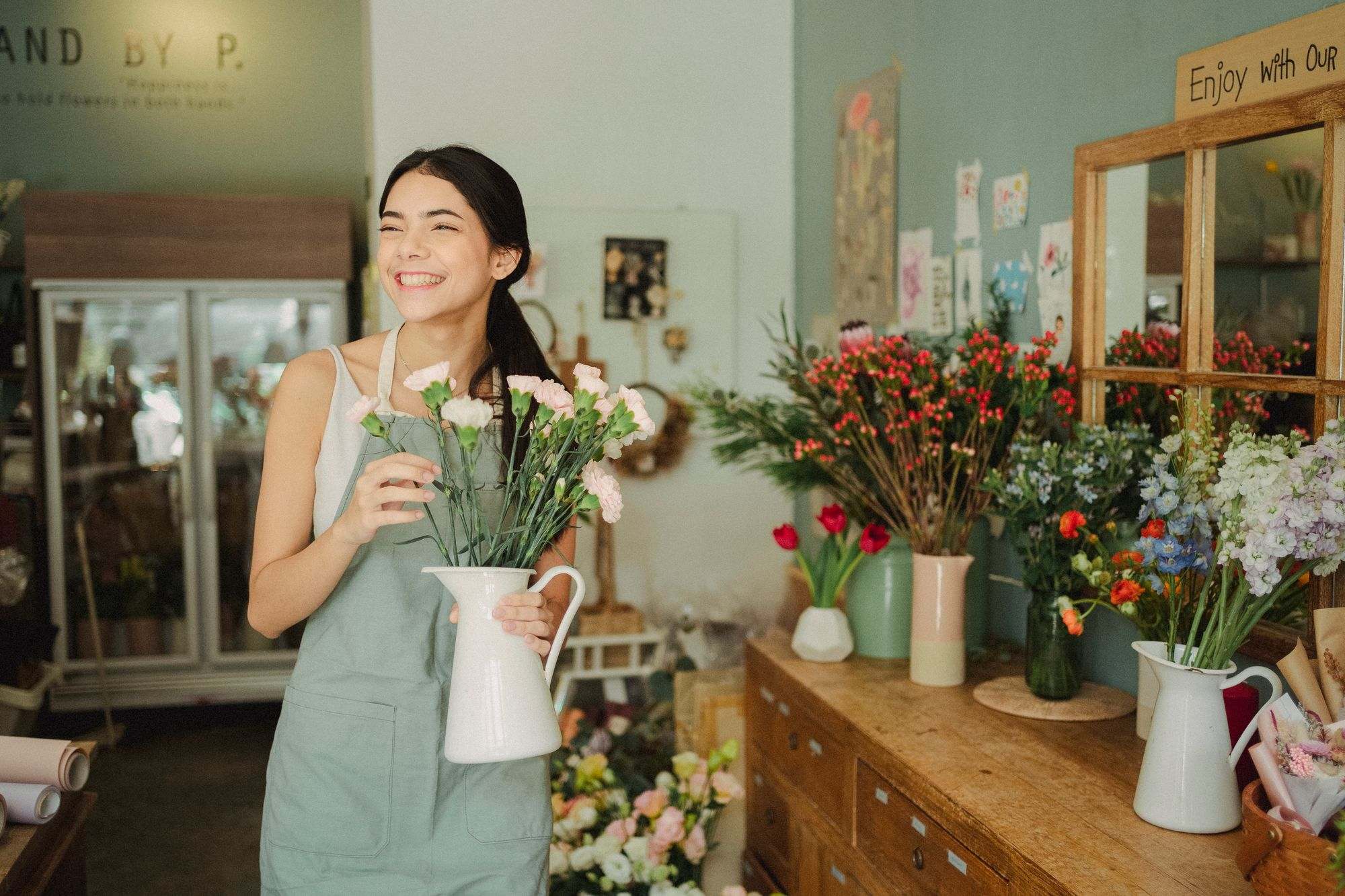 Una florista sonriente con un florero de flores blancas